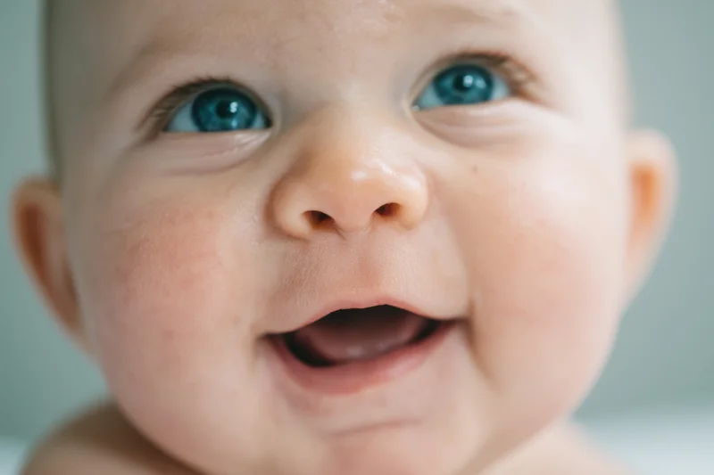 Close-up of a smiling baby with bright blue eyes looking upward