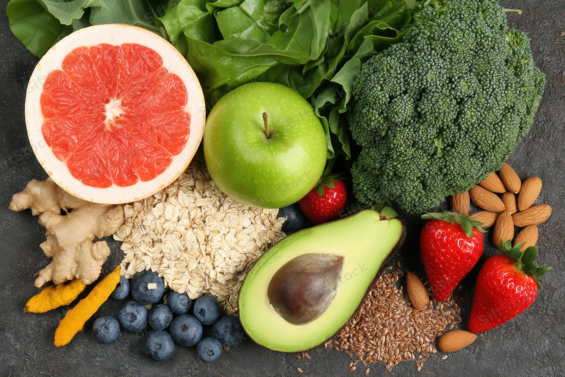 Top-down arrangement of fresh fruits vegetables grains on dark surface