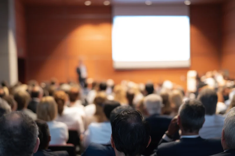 Audience seated in rows watching a speaker at a conference presentation