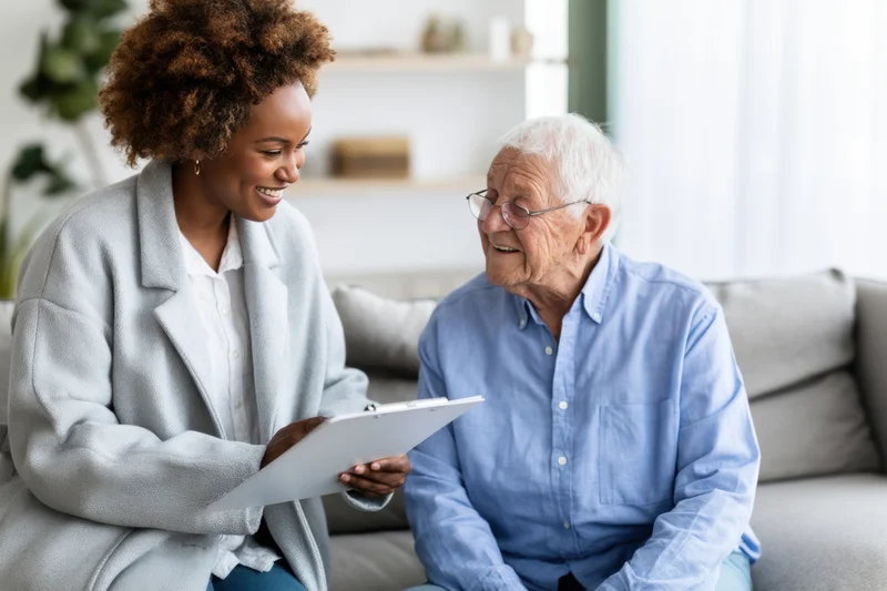 Female clinician consulting with elderly man on sofa in therapy room