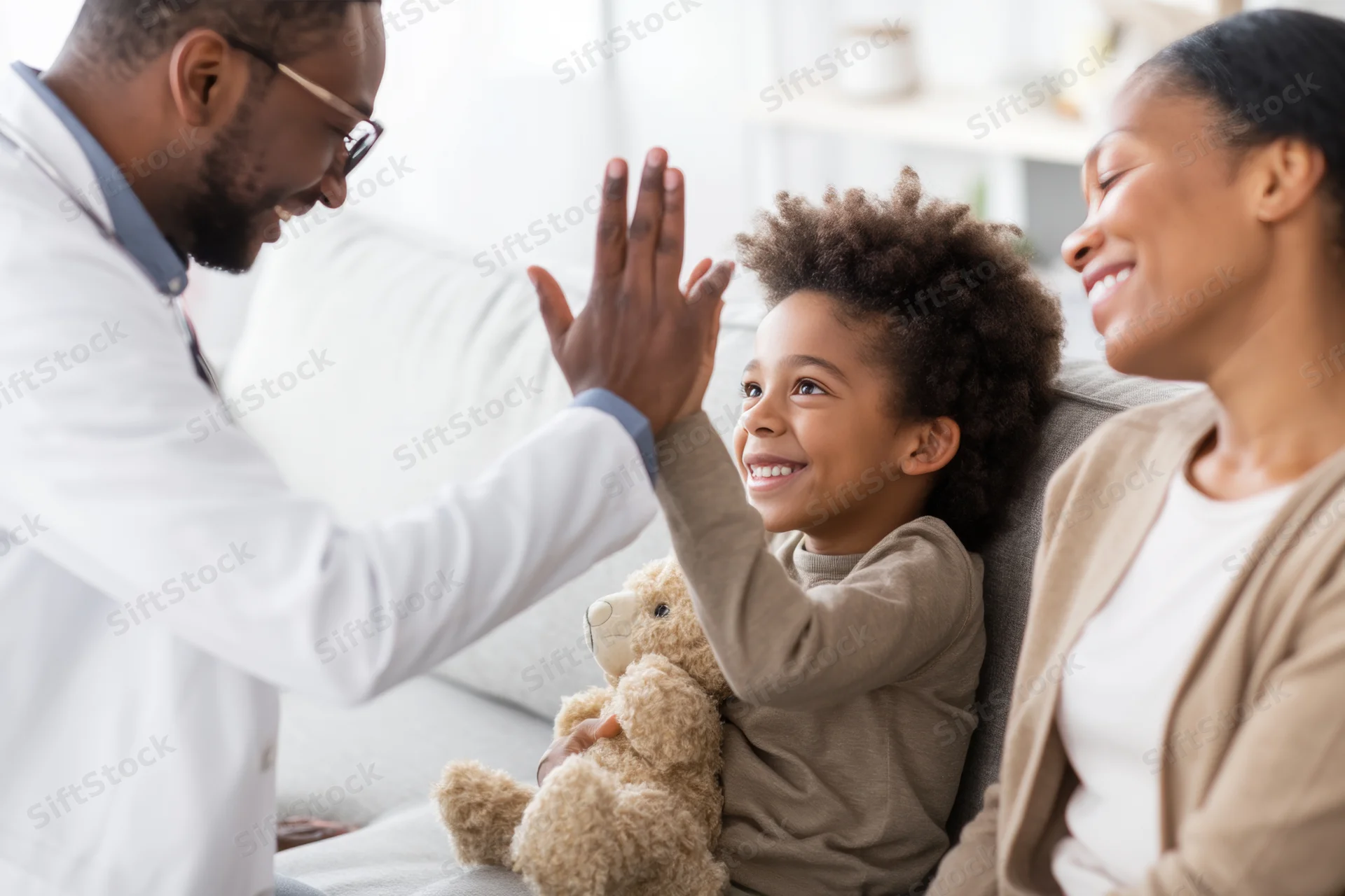 Doctor high-fiving child during home visit with mother present