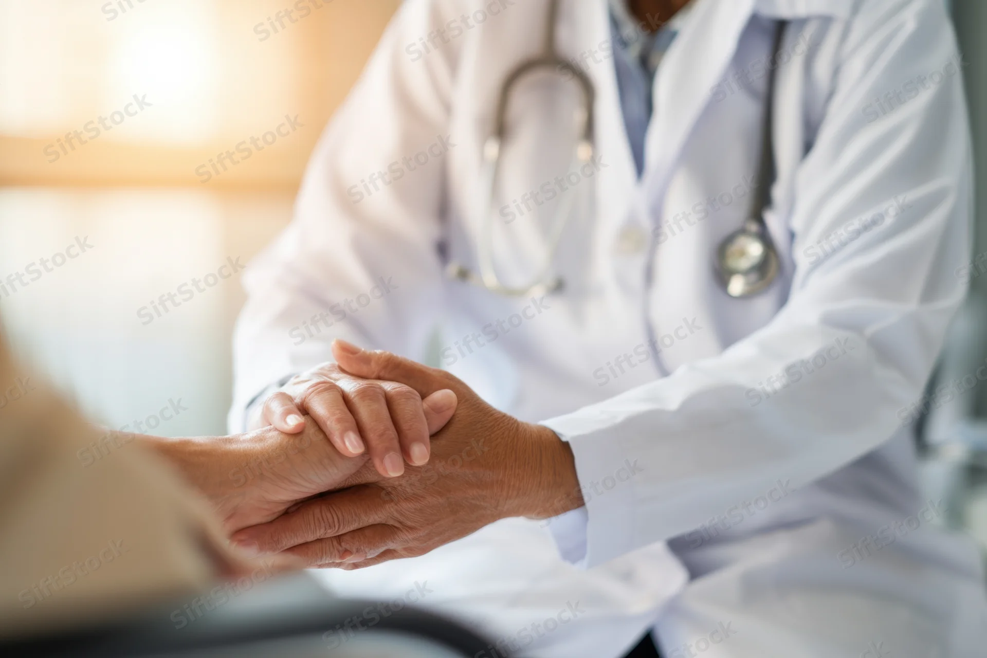 Doctor holding patient's hand during consultation in clinic