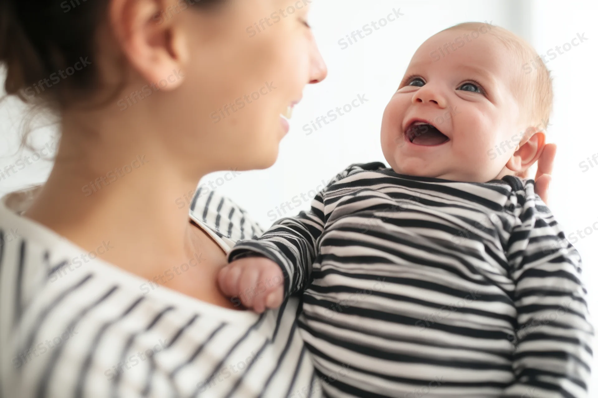 Baby smiling while being held by mother indoors