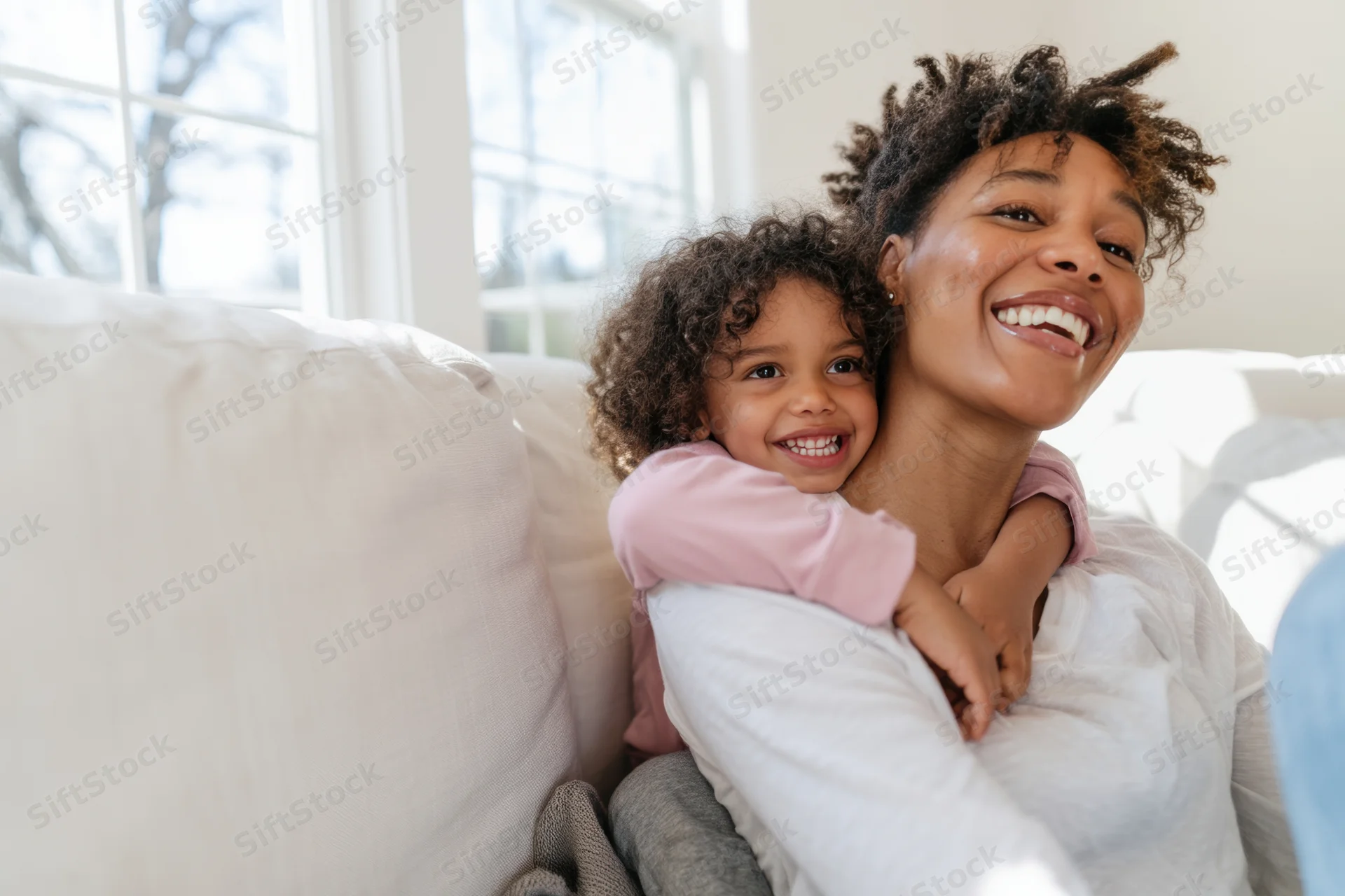 Mother hugging child on light-colored couch in living room
