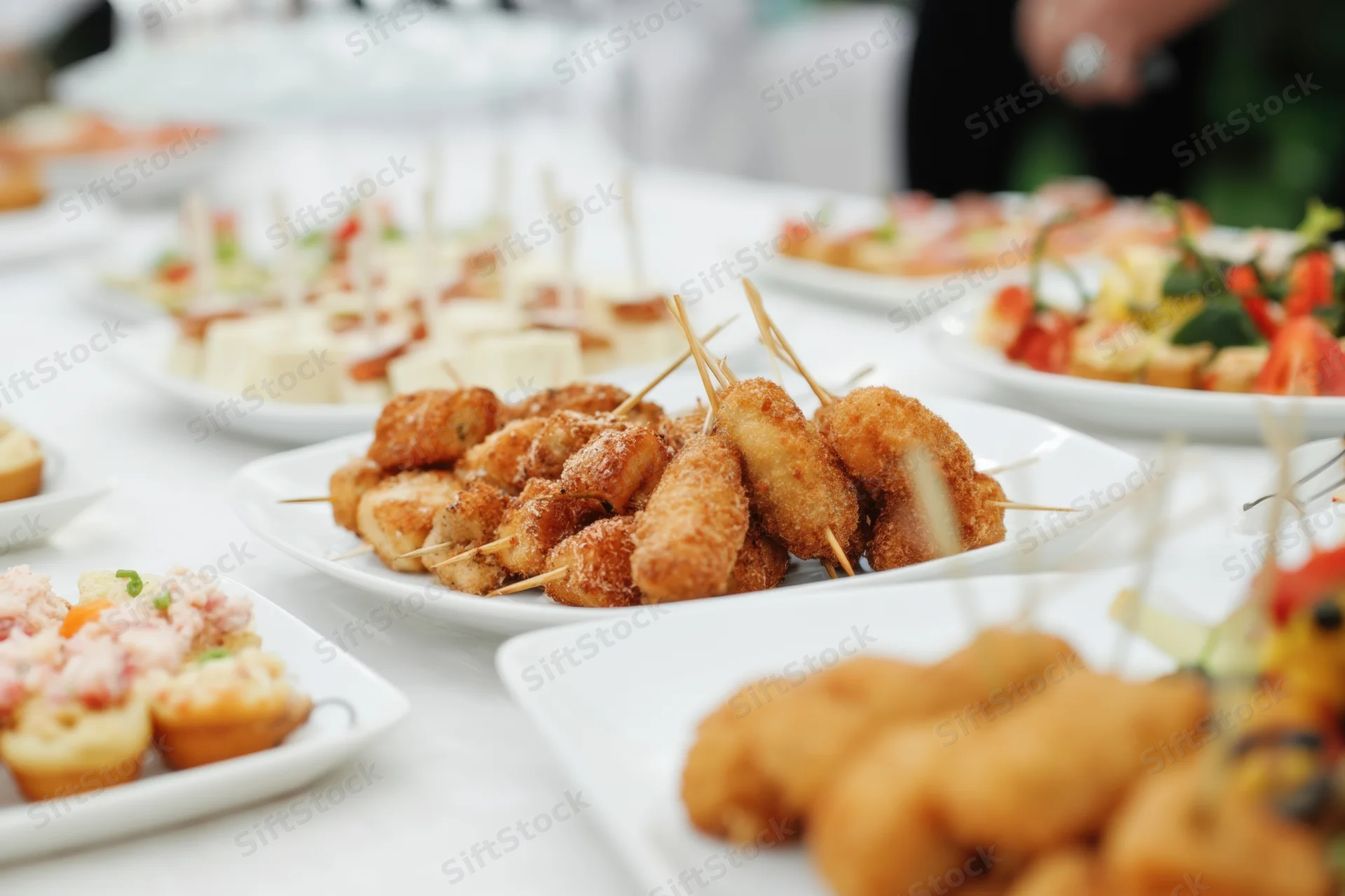 Assorted appetizers on white plates arranged on a buffet table