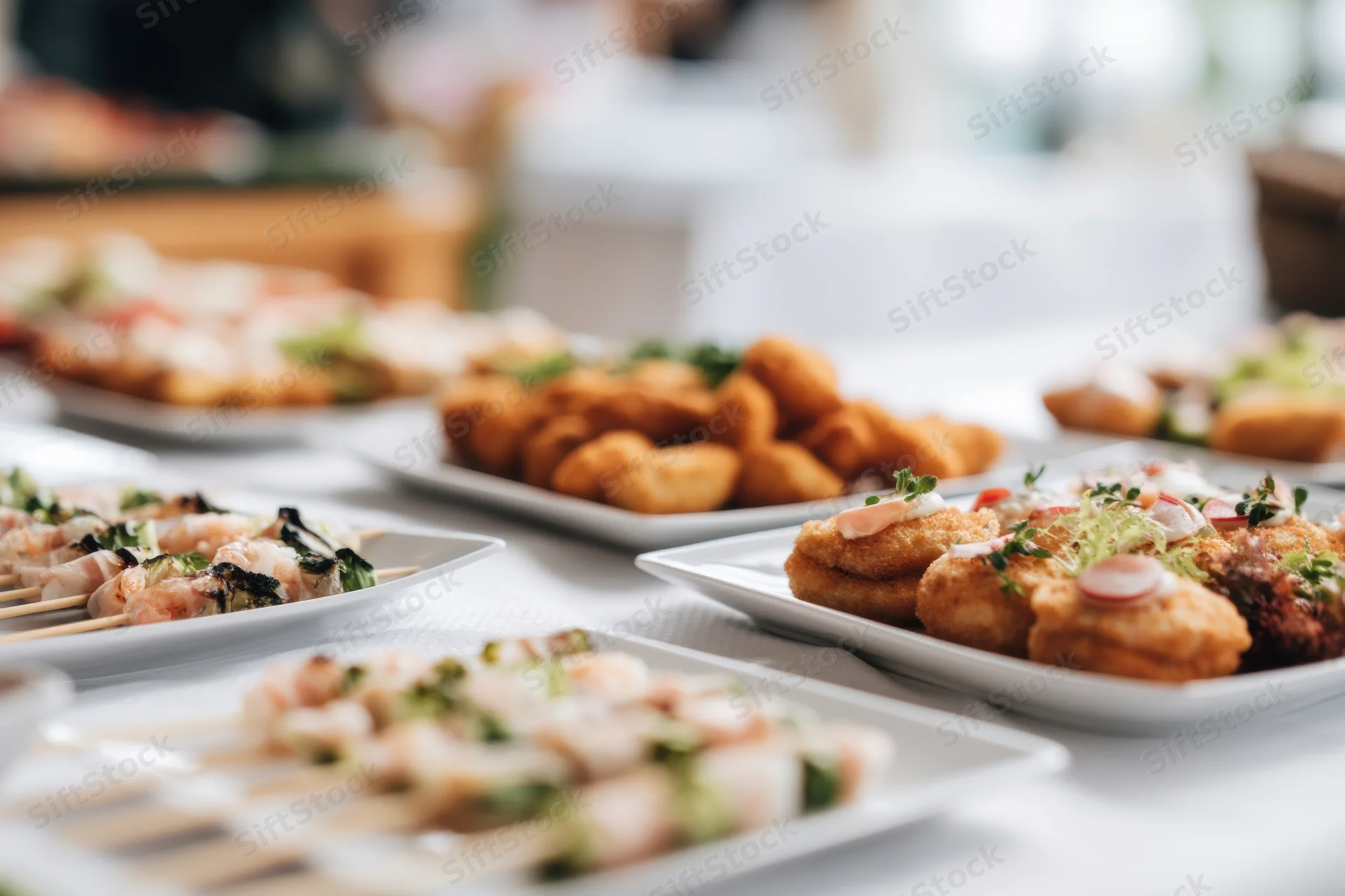 Buffet table with skewers and croquettes arranged on white plates for event dining
