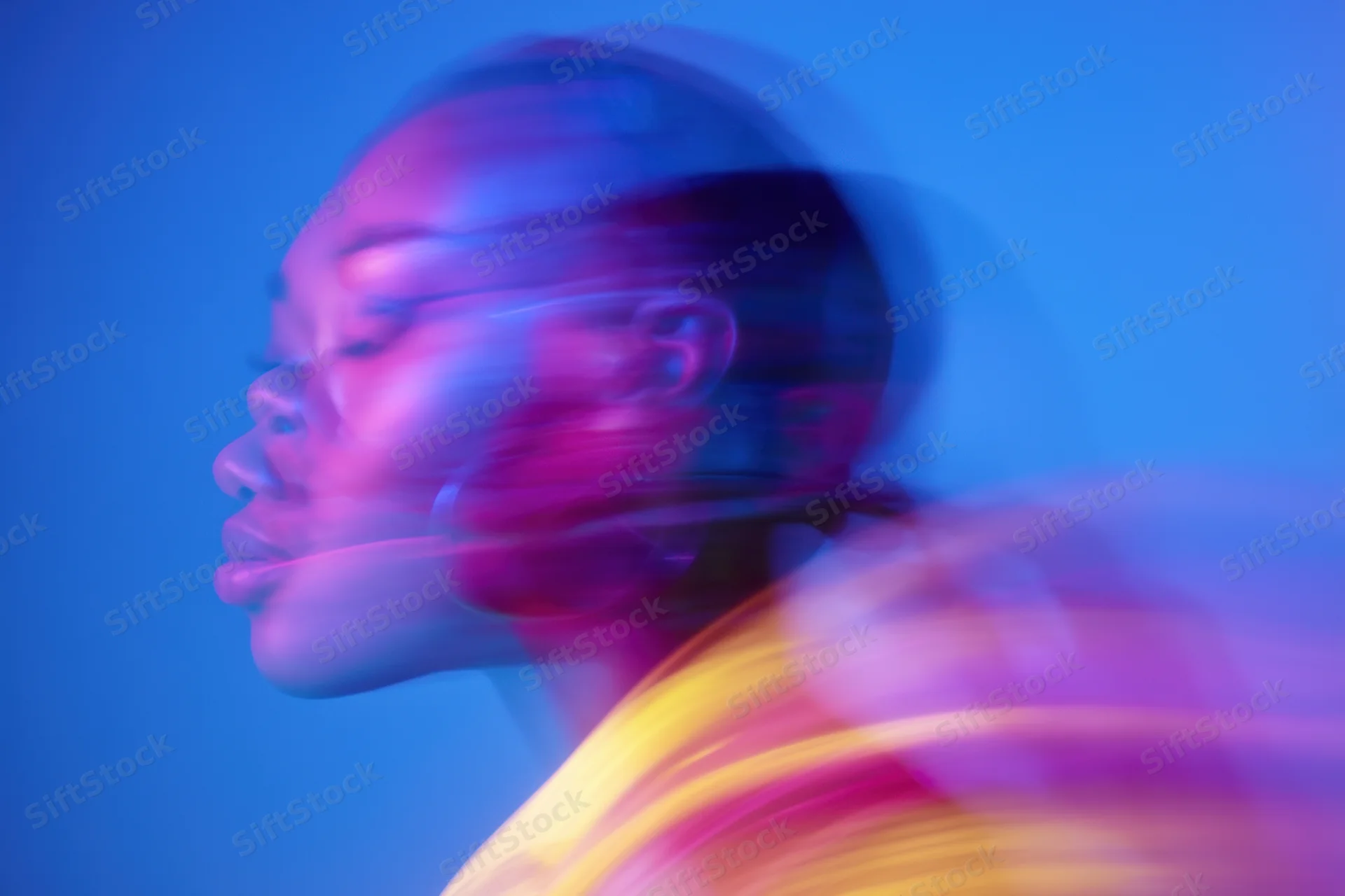 Woman in motion blur with neon pink and blue light in side profile
