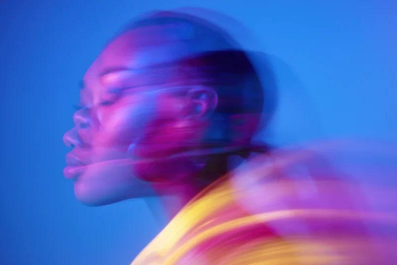Woman in motion blur with neon pink and blue light in side profile