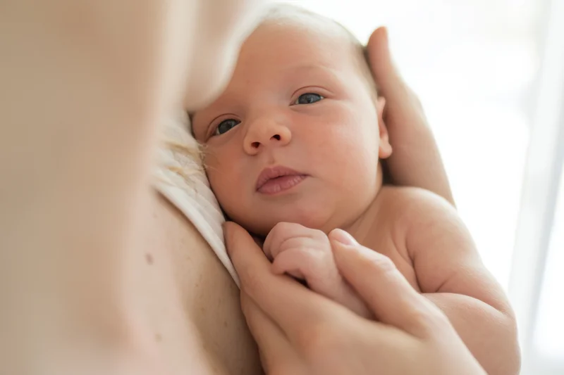 Newborn baby cradled in mother’s hands, eyes open, close-up view