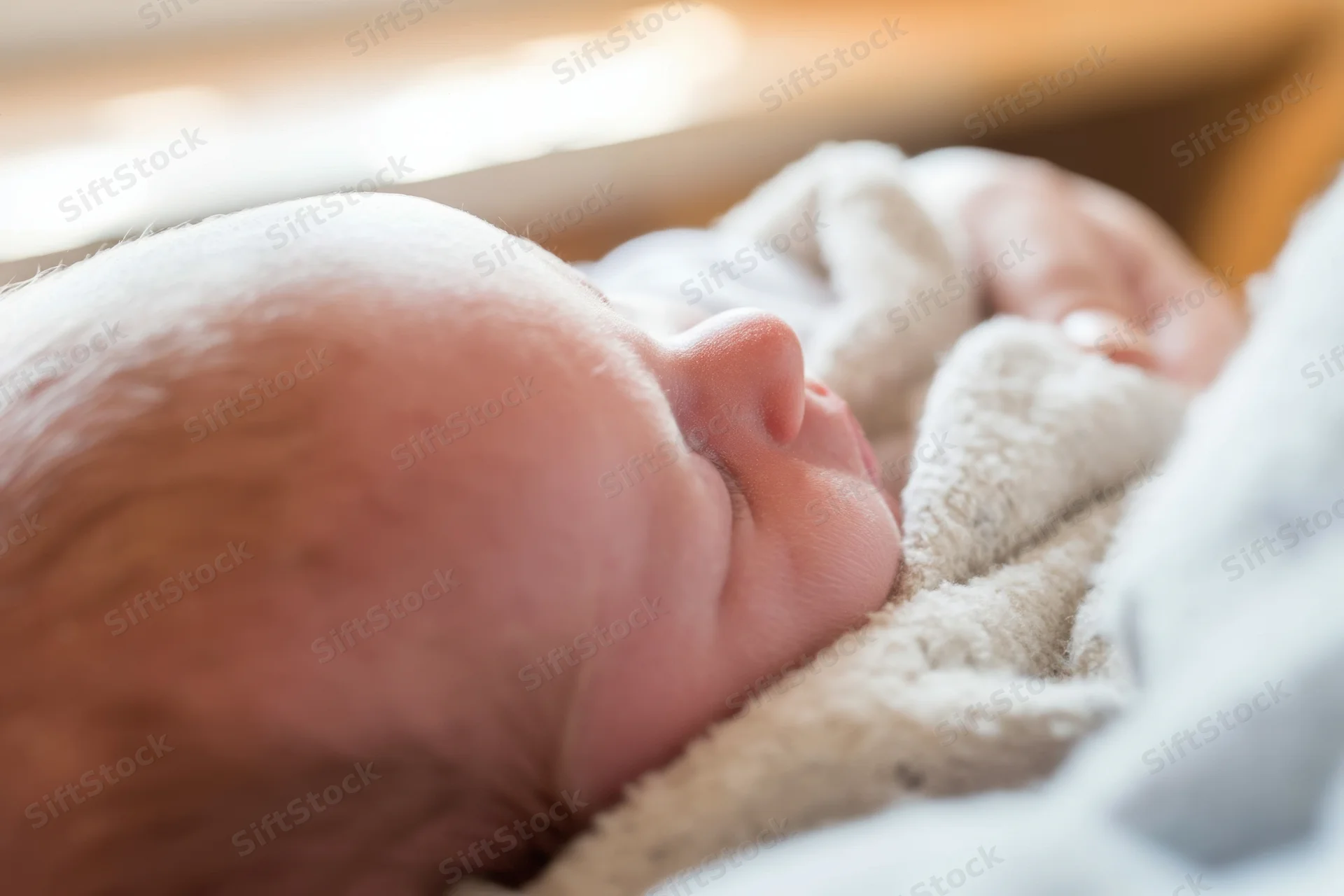 Newborn baby sleeping peacefully on a soft blanket in a warm indoor setting