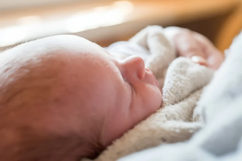 Newborn baby sleeping peacefully on a soft blanket in a warm indoor setting