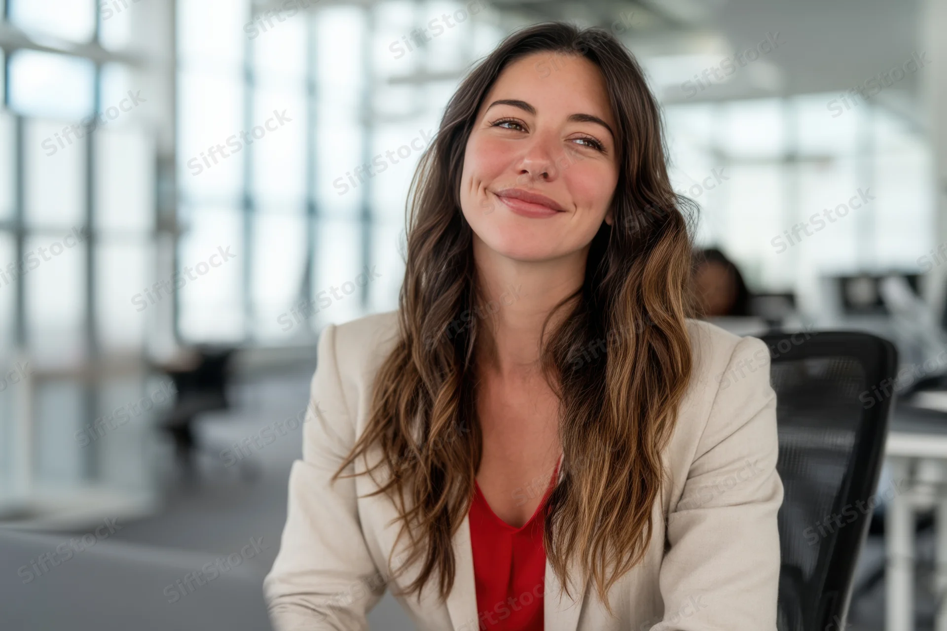 Woman in beige jacket smiling in modern office setting