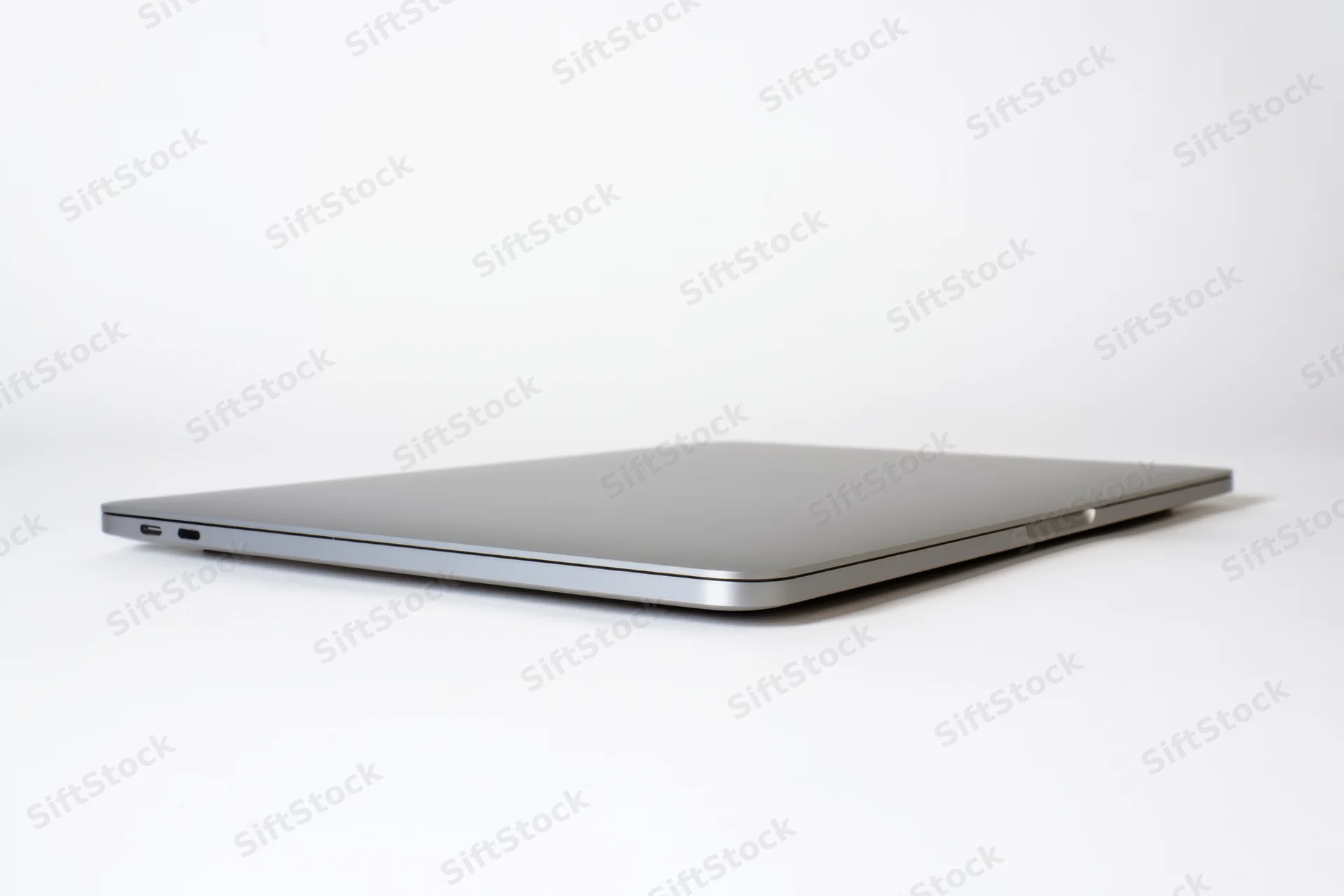 Closed sleek aluminum laptop viewed from side on white background