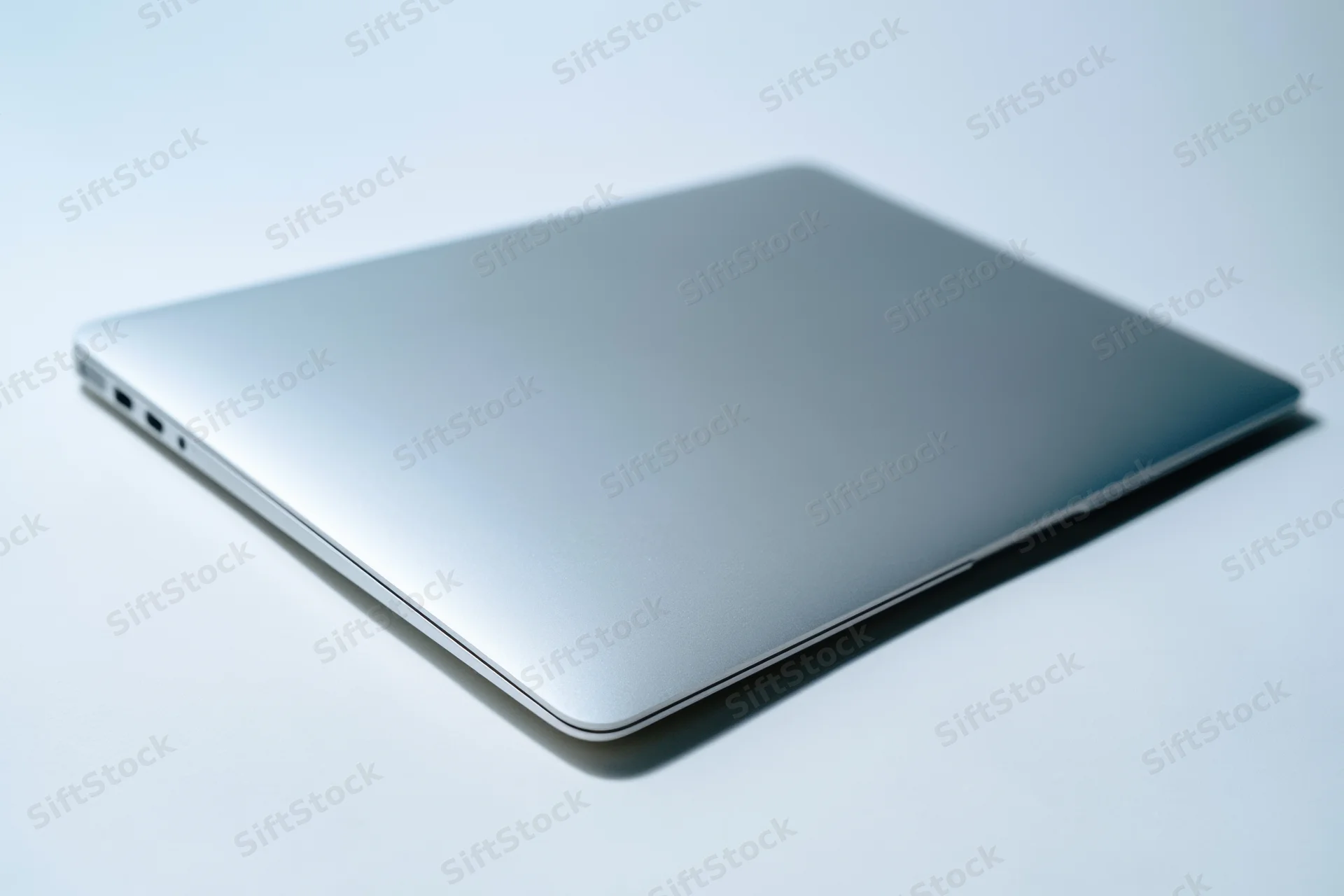 Closed silver laptop resting on a white surface in a studio setting