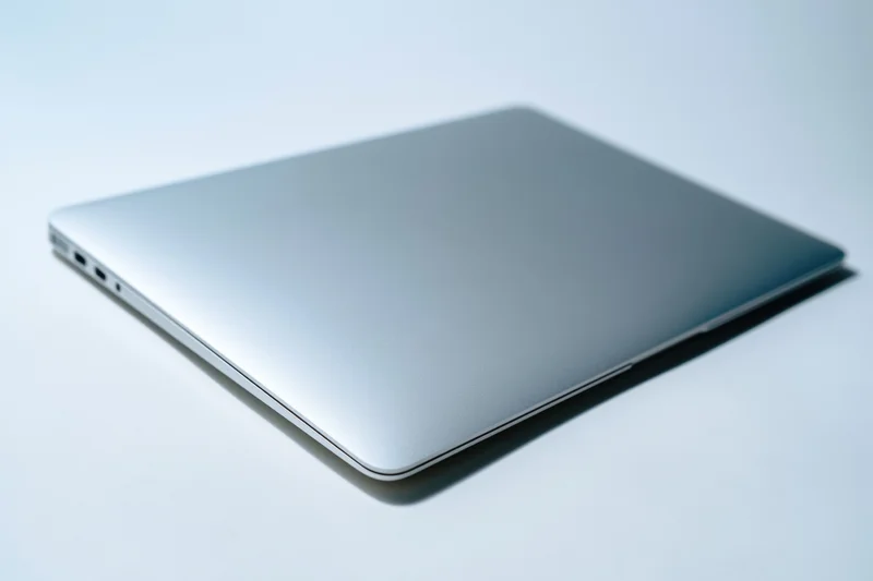 Closed silver laptop resting on a white surface in a studio setting