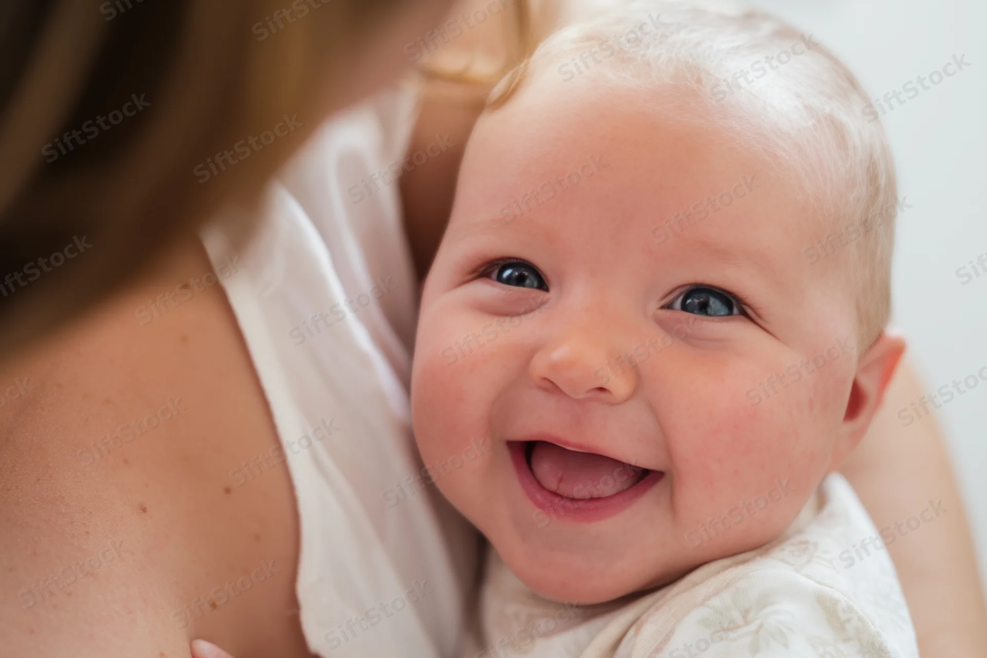 Smiling baby held close in a caregiver’s arms