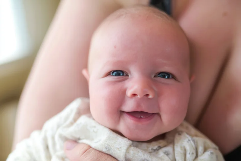 Smiling baby held in caregiver's arms close-up