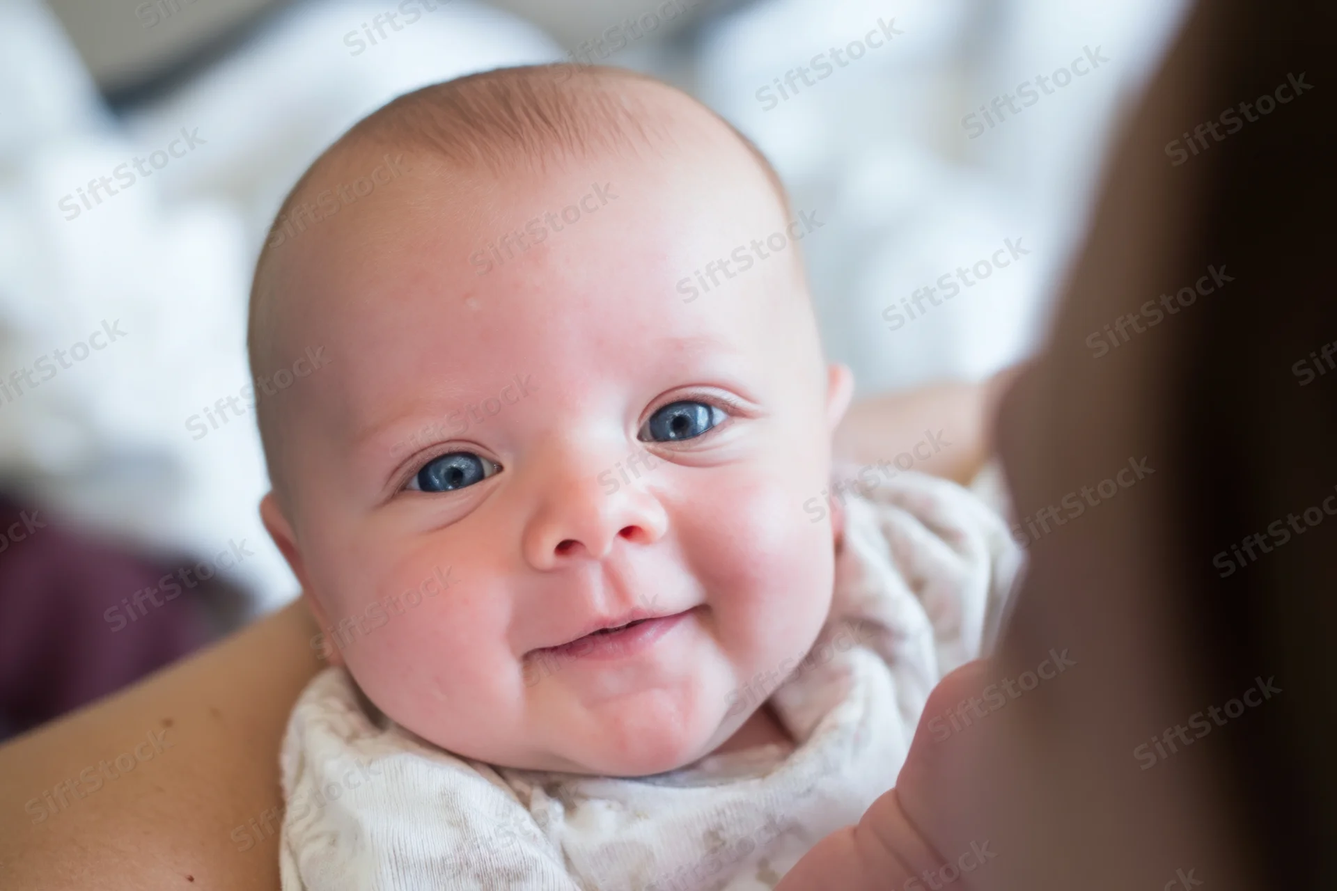 Smiling infant held in caregiver's arms close-up