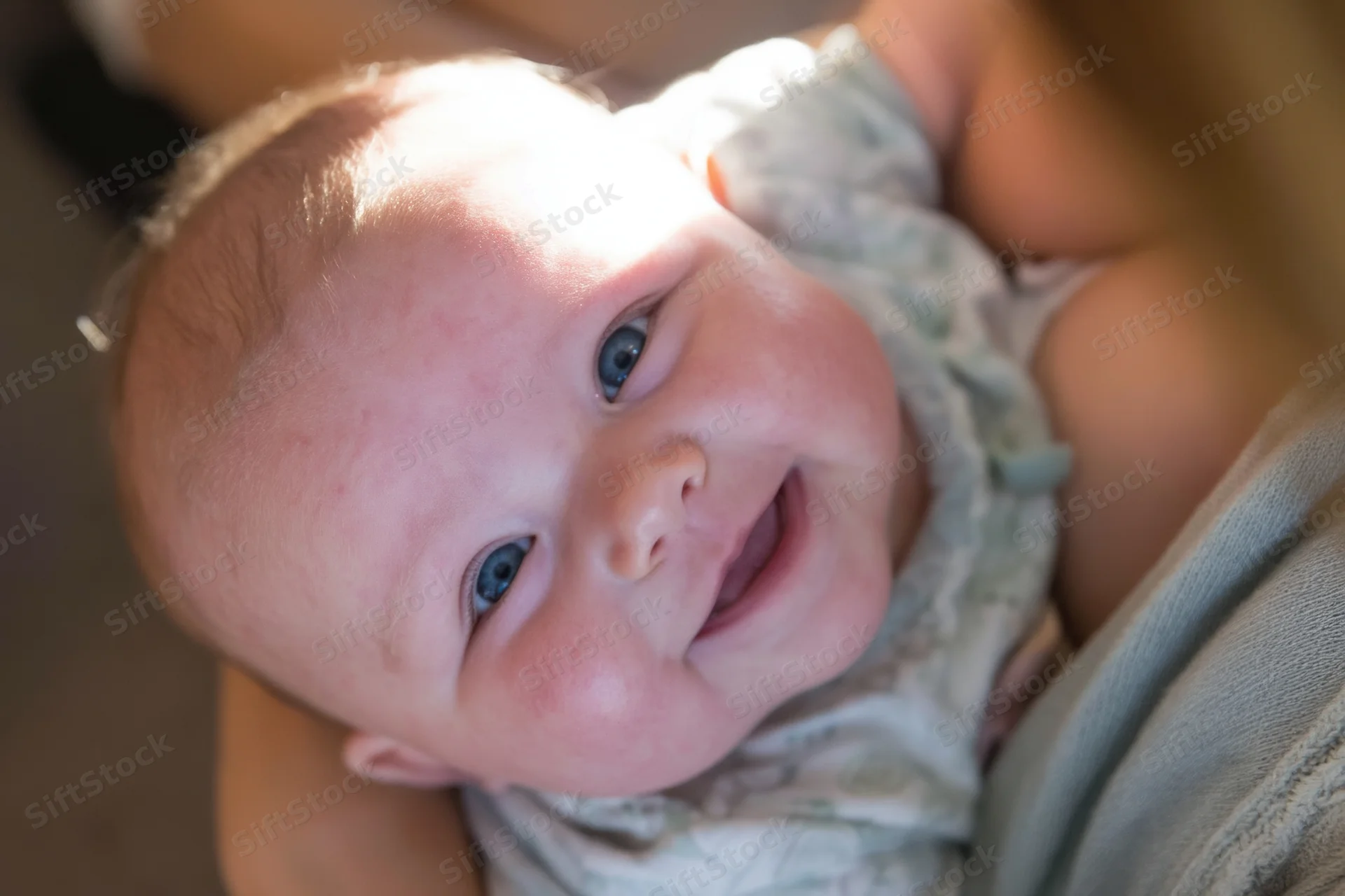 Smiling infant held in caregiver's arms close-up