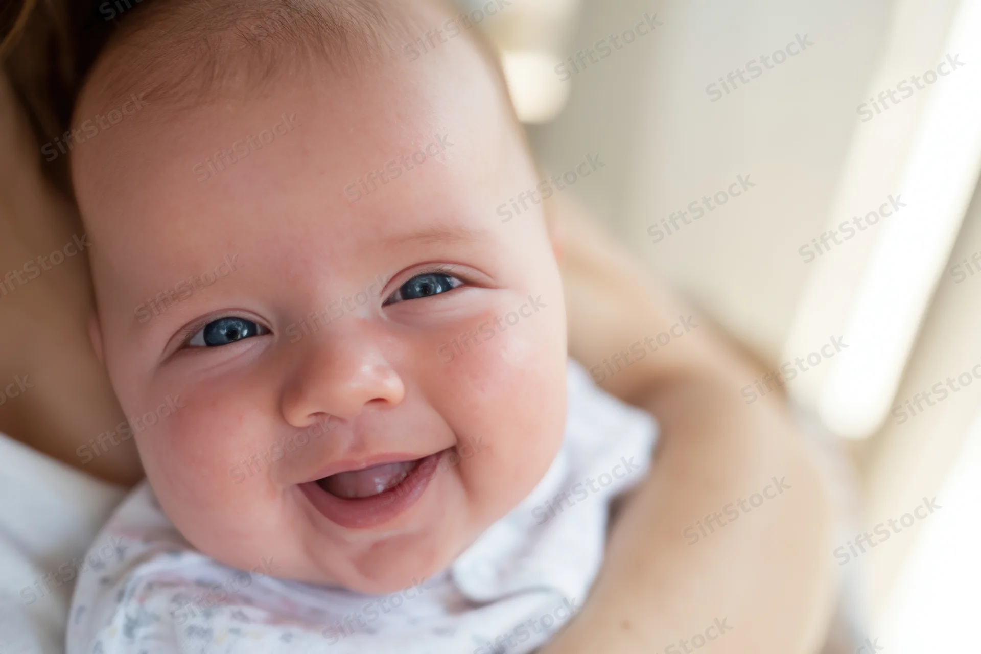 Smiling baby held in caregiver's arms close-up