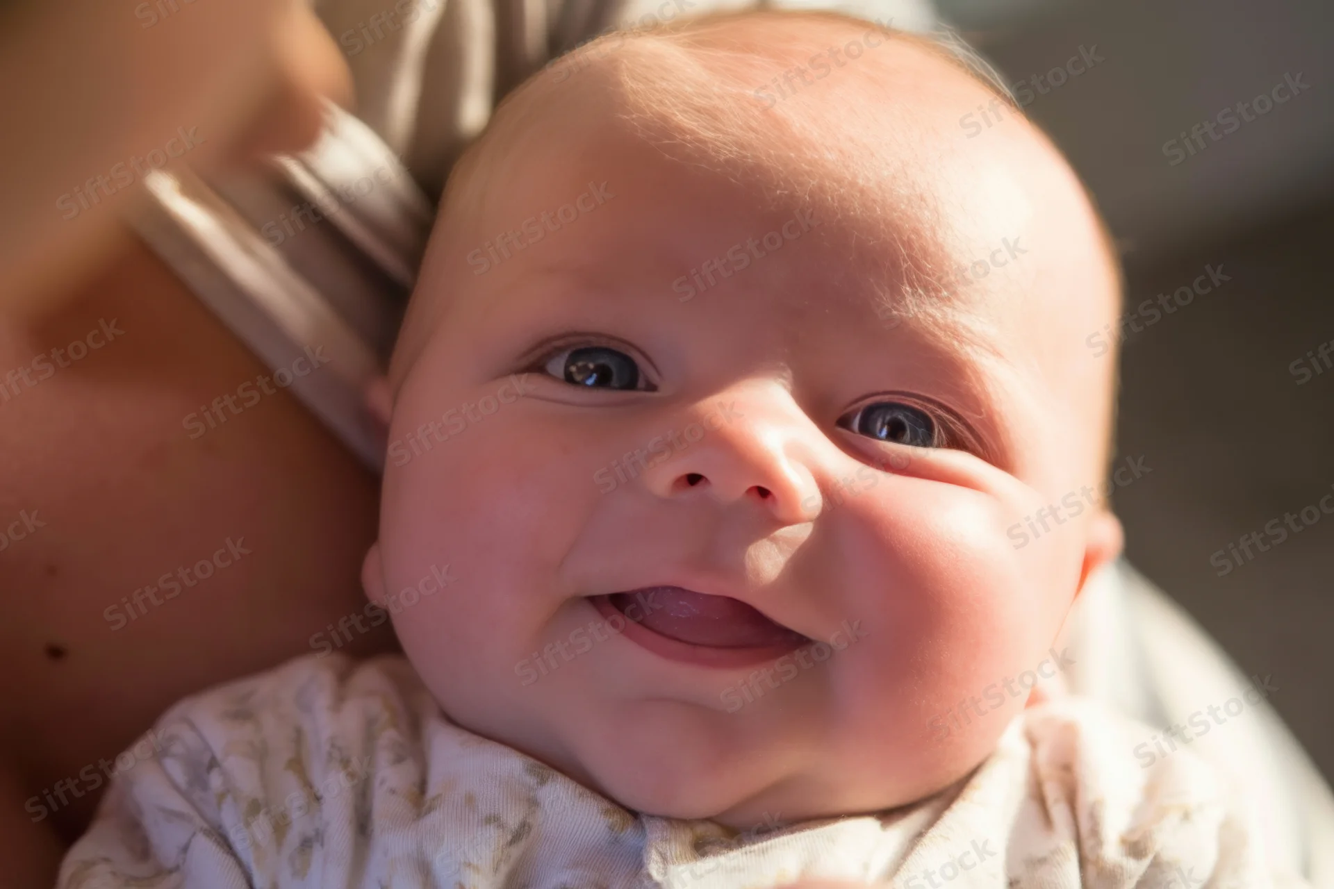 Smiling baby held in caregiver's arms close-up