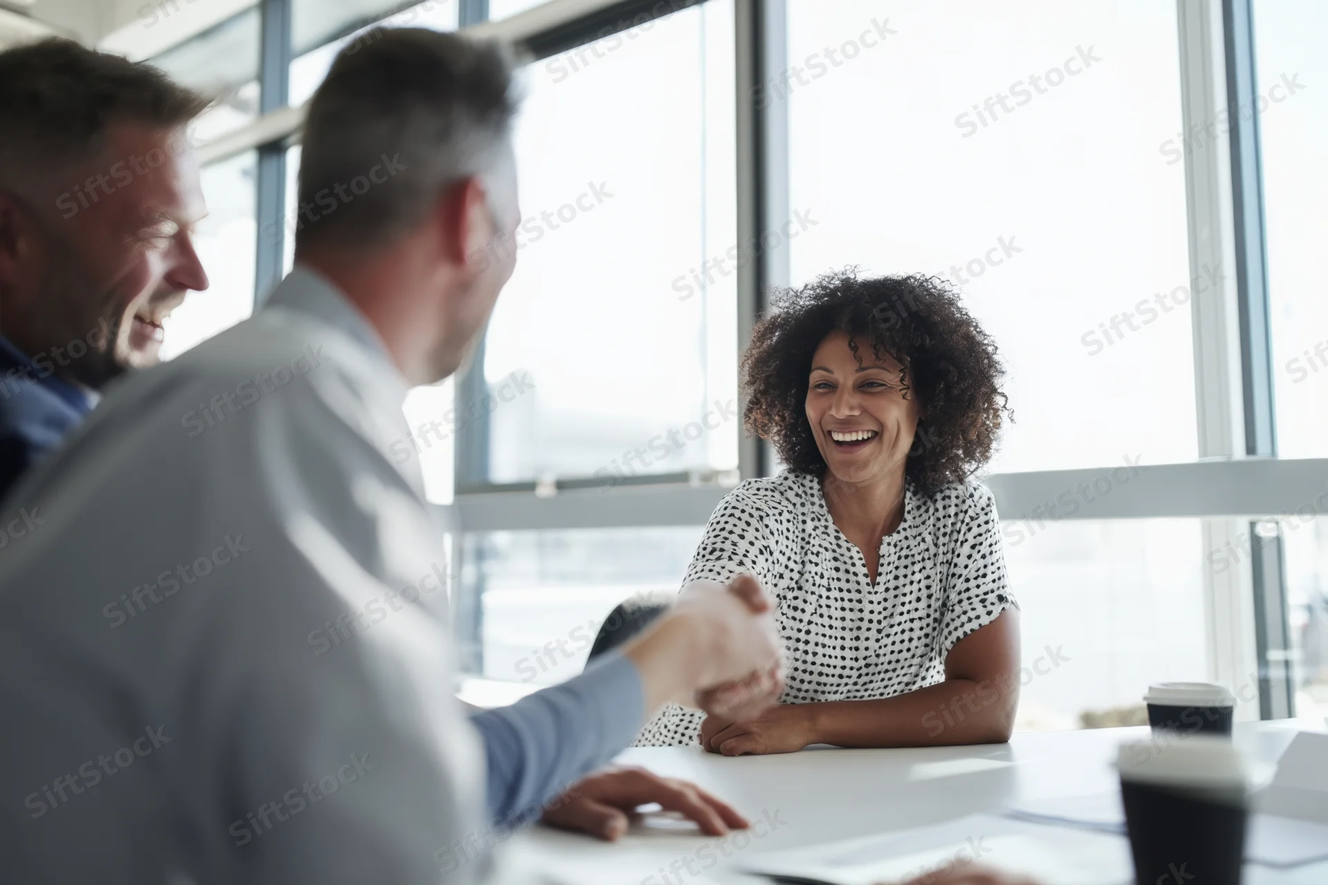 Woman and man shaking hands across conference table in office meeting