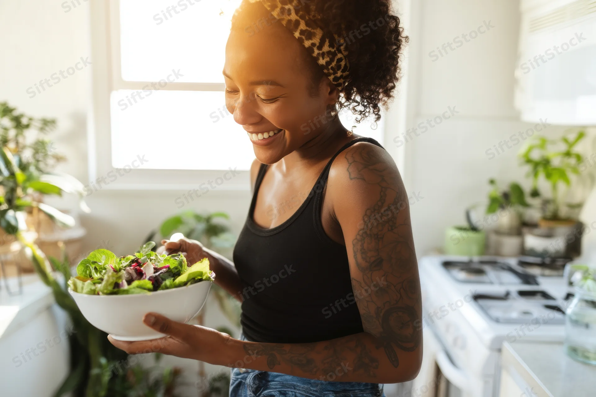 Smiling woman holding a bowl of salad in a bright kitchen