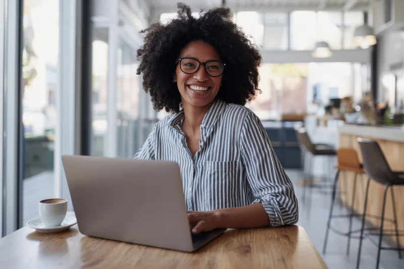 Woman smiling at laptop on wooden desk in modern office space