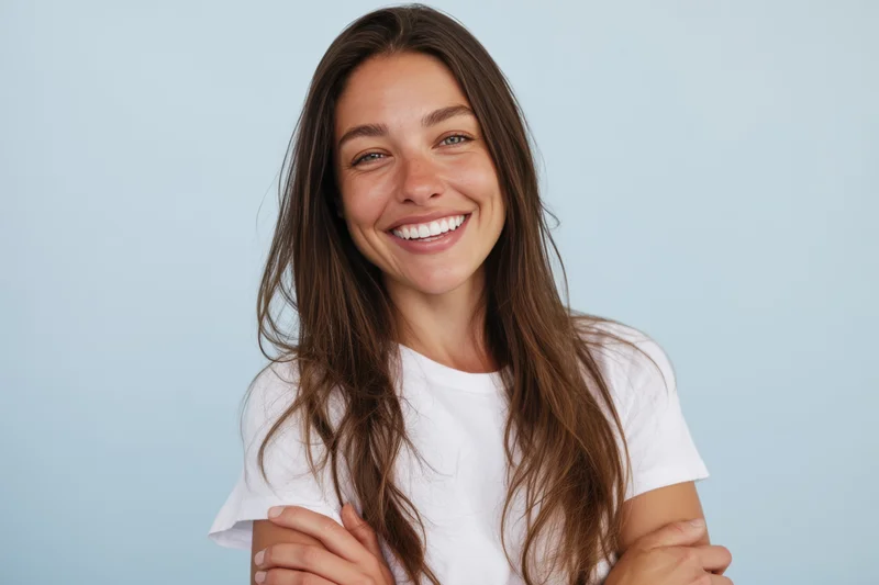 Smiling woman with long brown hair wearing white tshirt in studio setting