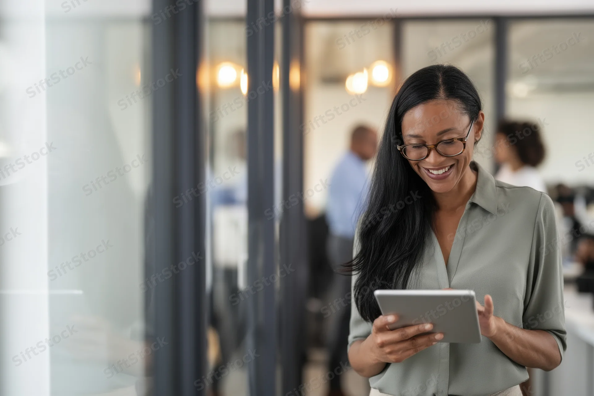 Smiling woman holding tablet in modern office space