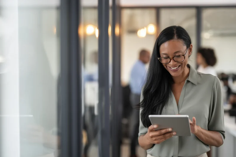 Smiling woman holding tablet in modern office space