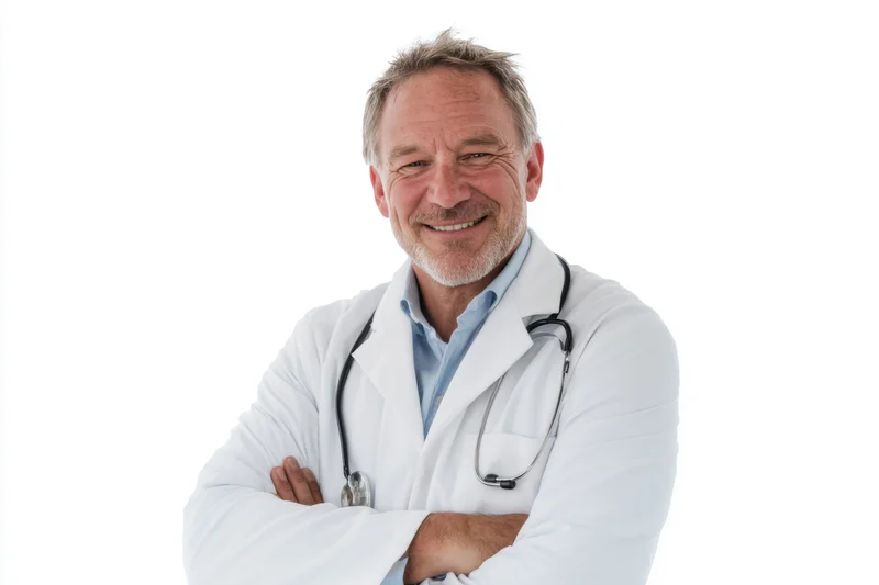 Male doctor in white lab coat with stethoscope smiling with arms crossed against white background