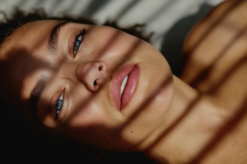 Woman lying on side with sunlight and shadows on her face