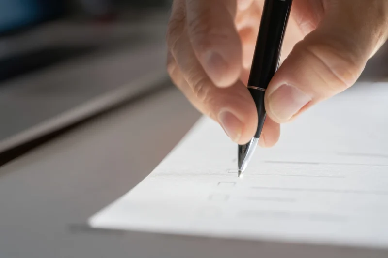 Hand writing on a document with a pen at a desk