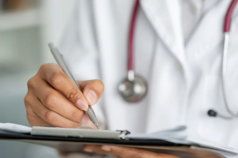 Doctor writing notes on a clipboard in a clinic setting