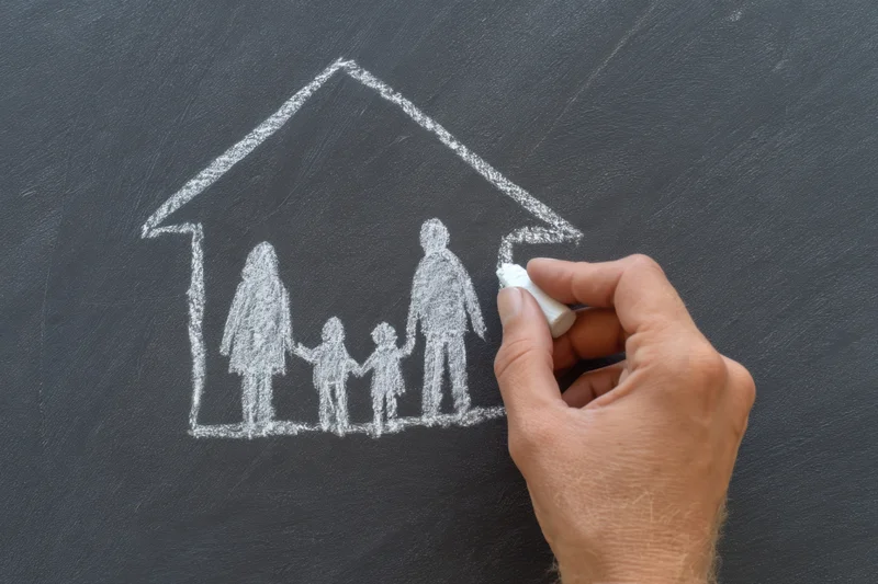 Hand drawing chalk sketch of family under house roof on blackboard