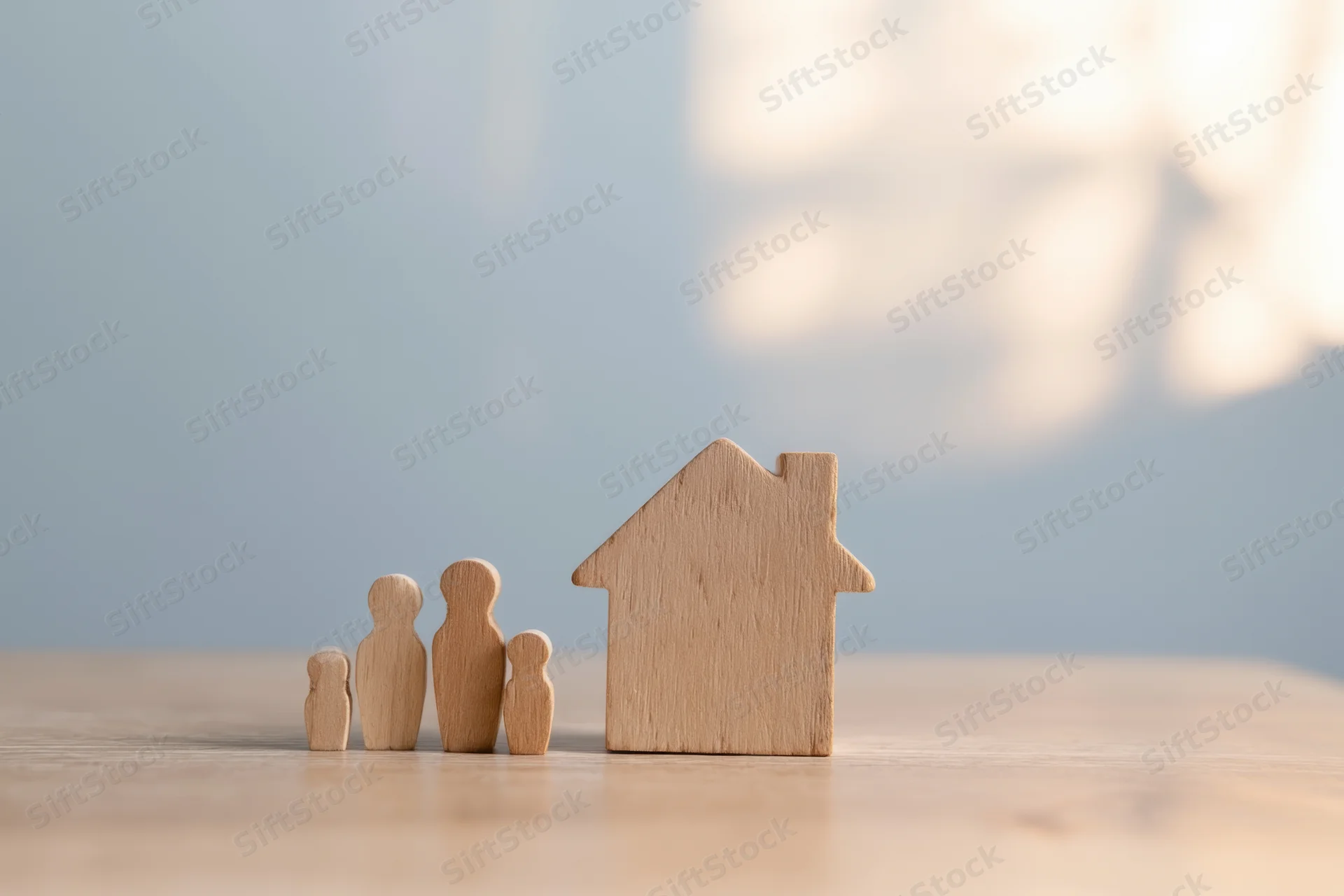 Wooden family figures and house model on a table surface