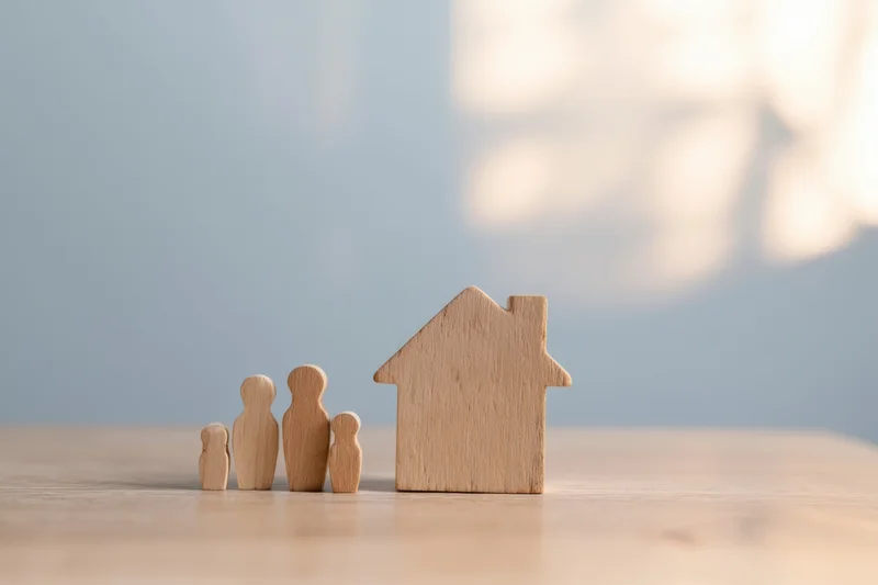 Wooden family figures and house model on a table surface