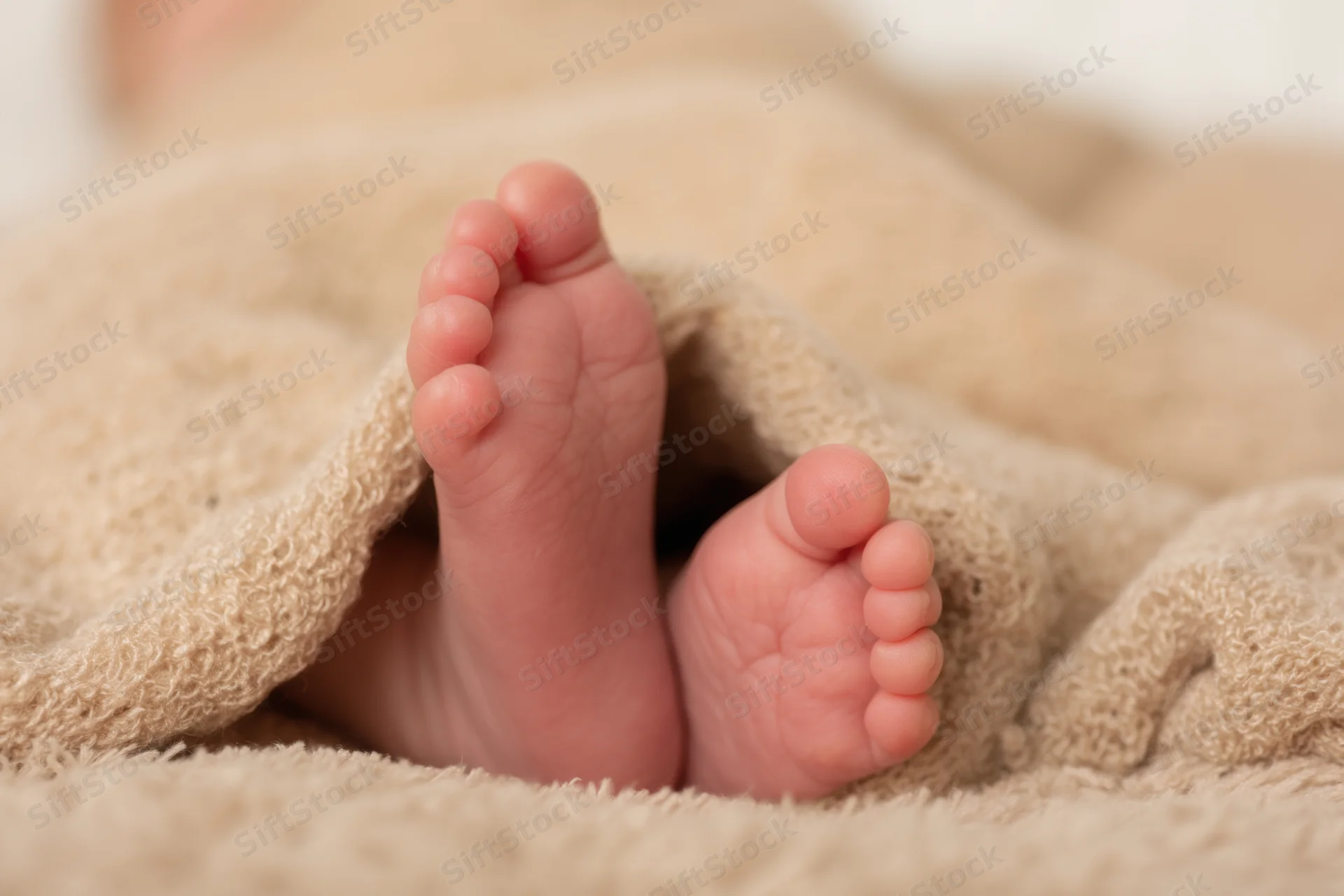 Baby's tiny feet peeking from beneath a soft textured blanket