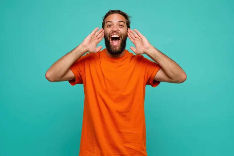 Joyful man with beard shouting with hands near face against turquoise background