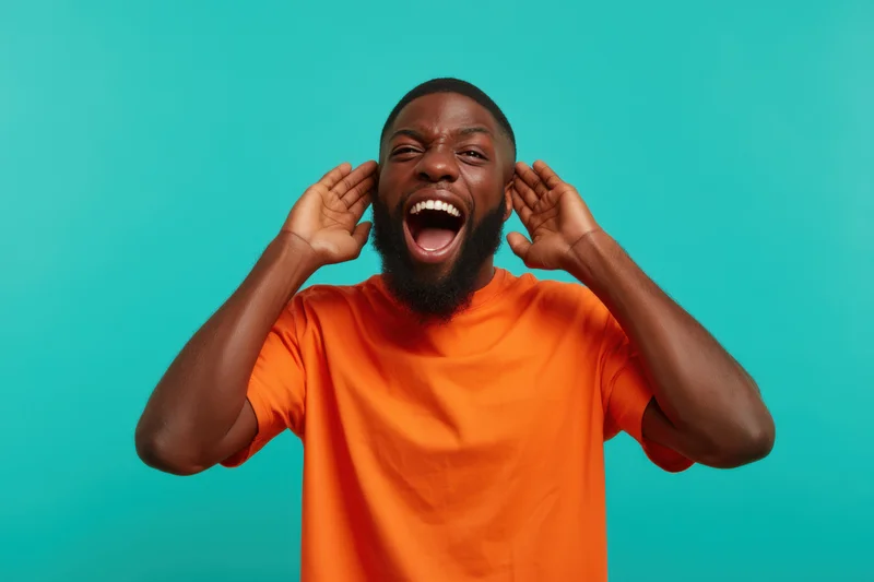 Man shouting with hands on ears in orange t-shirt against turquoise background