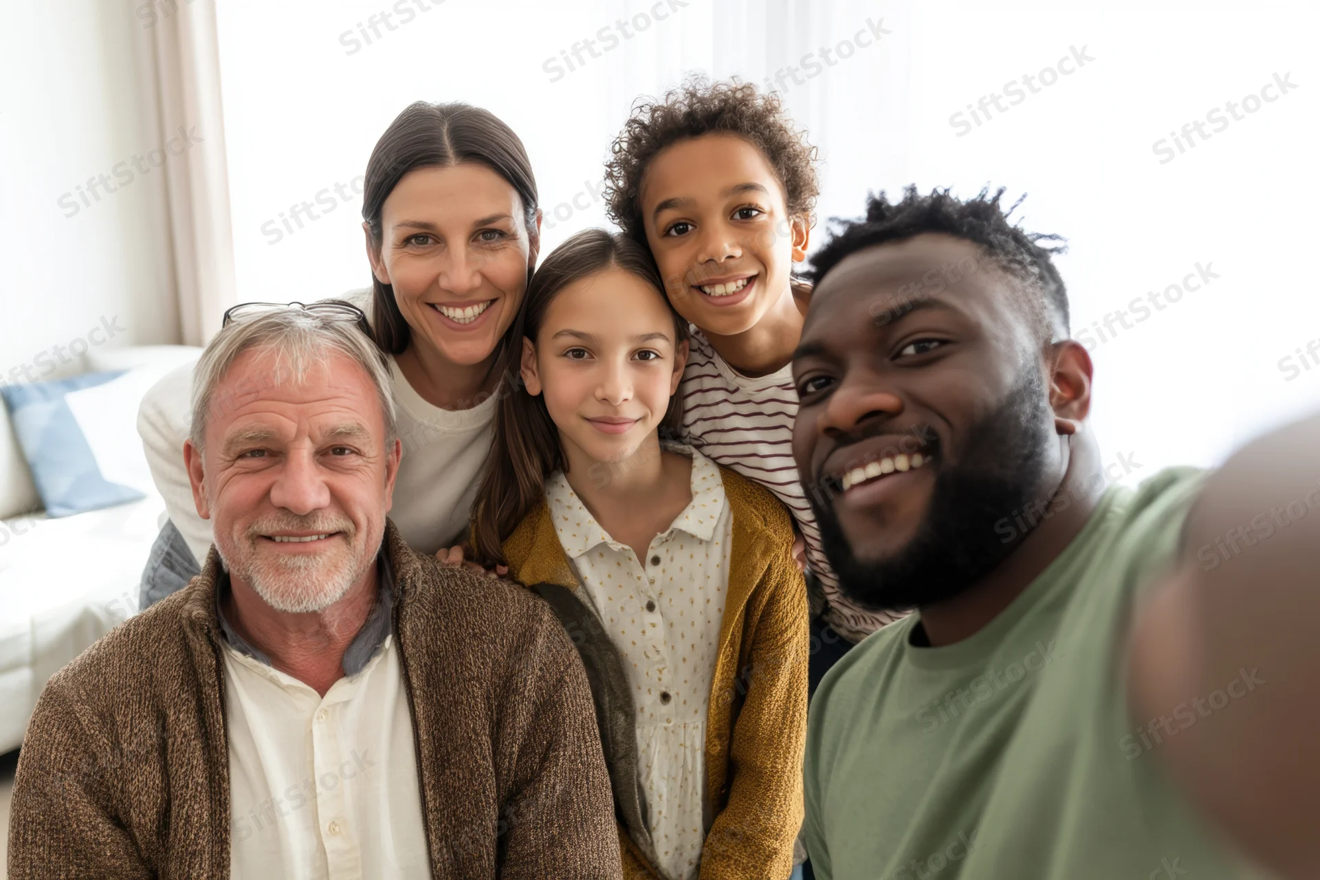 Multi-generational family smiling for a selfie in a bright living room