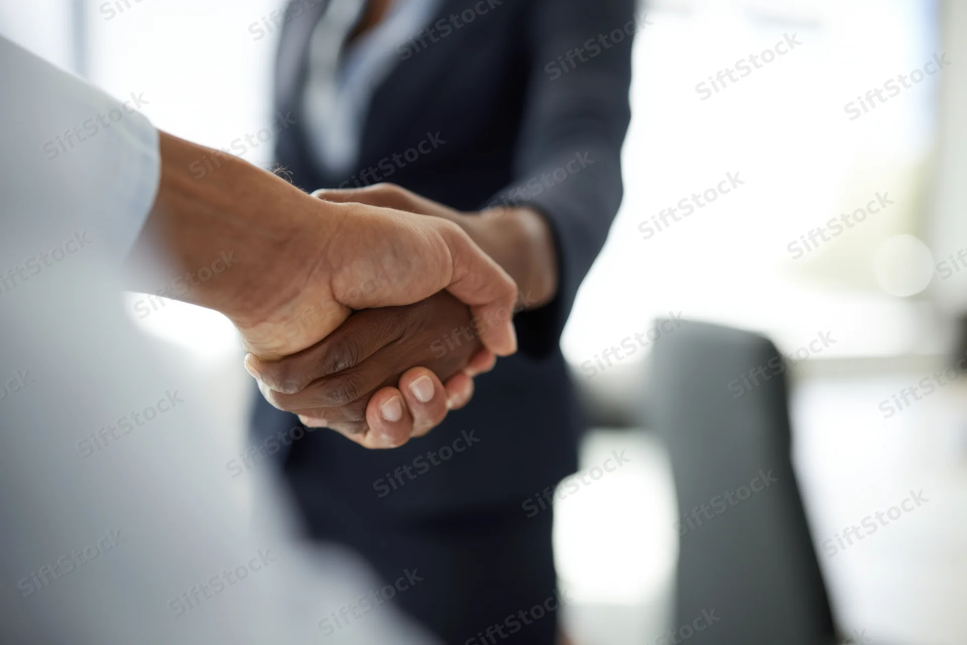 Close-up of two professionals shaking hands in an office meeting