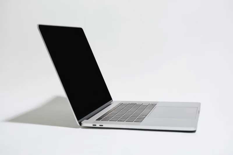 Slim silver laptop open with black screen on white background