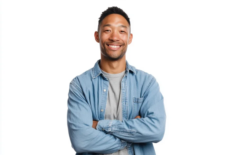 Smiling man with arms crossed wearing denim shirt over grey t-shirt against white background