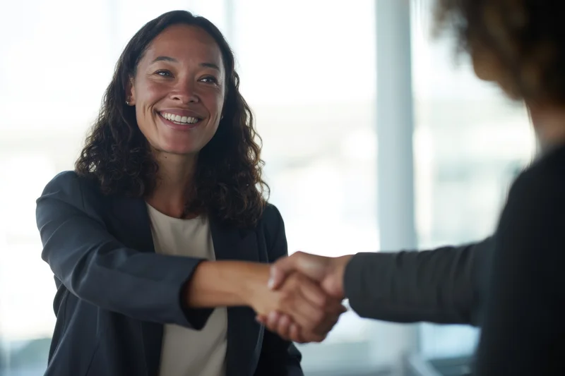 Woman smiling while shaking hands in an office setting
