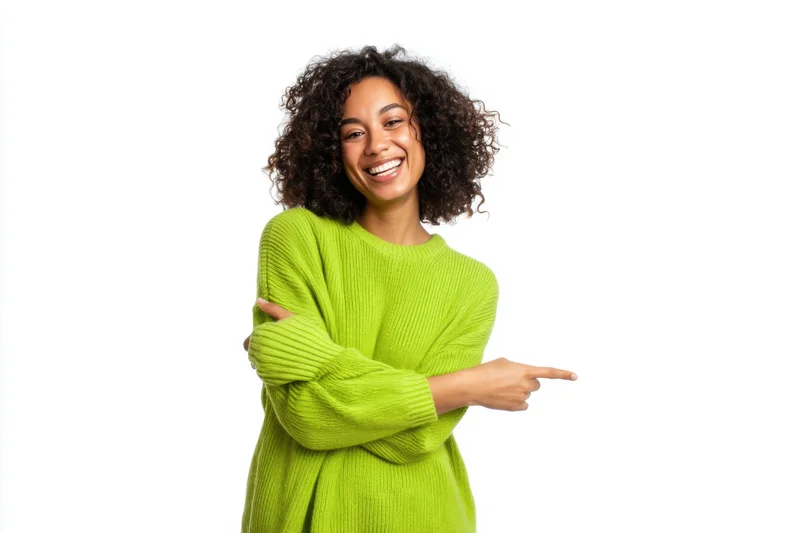 Smiling woman in green sweater pointing to the side against white background