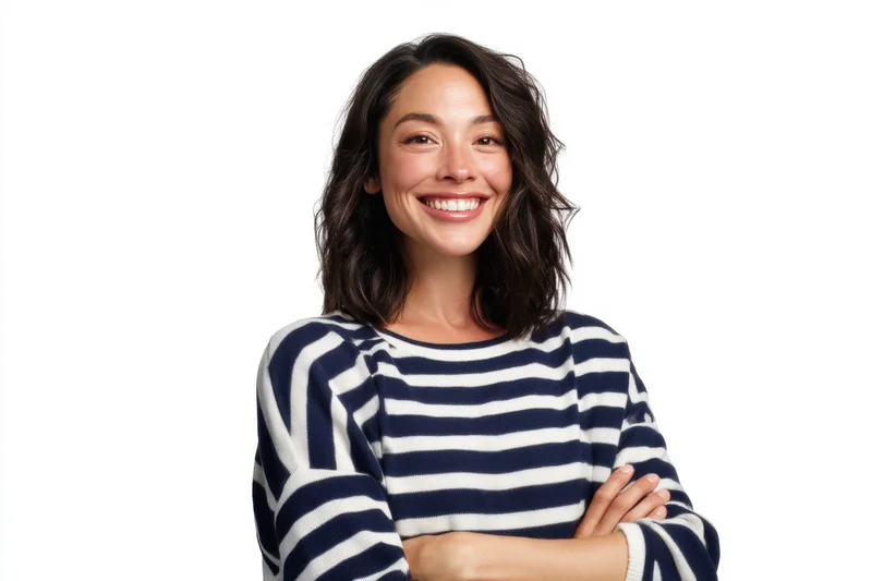 Smiling woman with arms crossed wearing a navy and white striped sweater against a white background