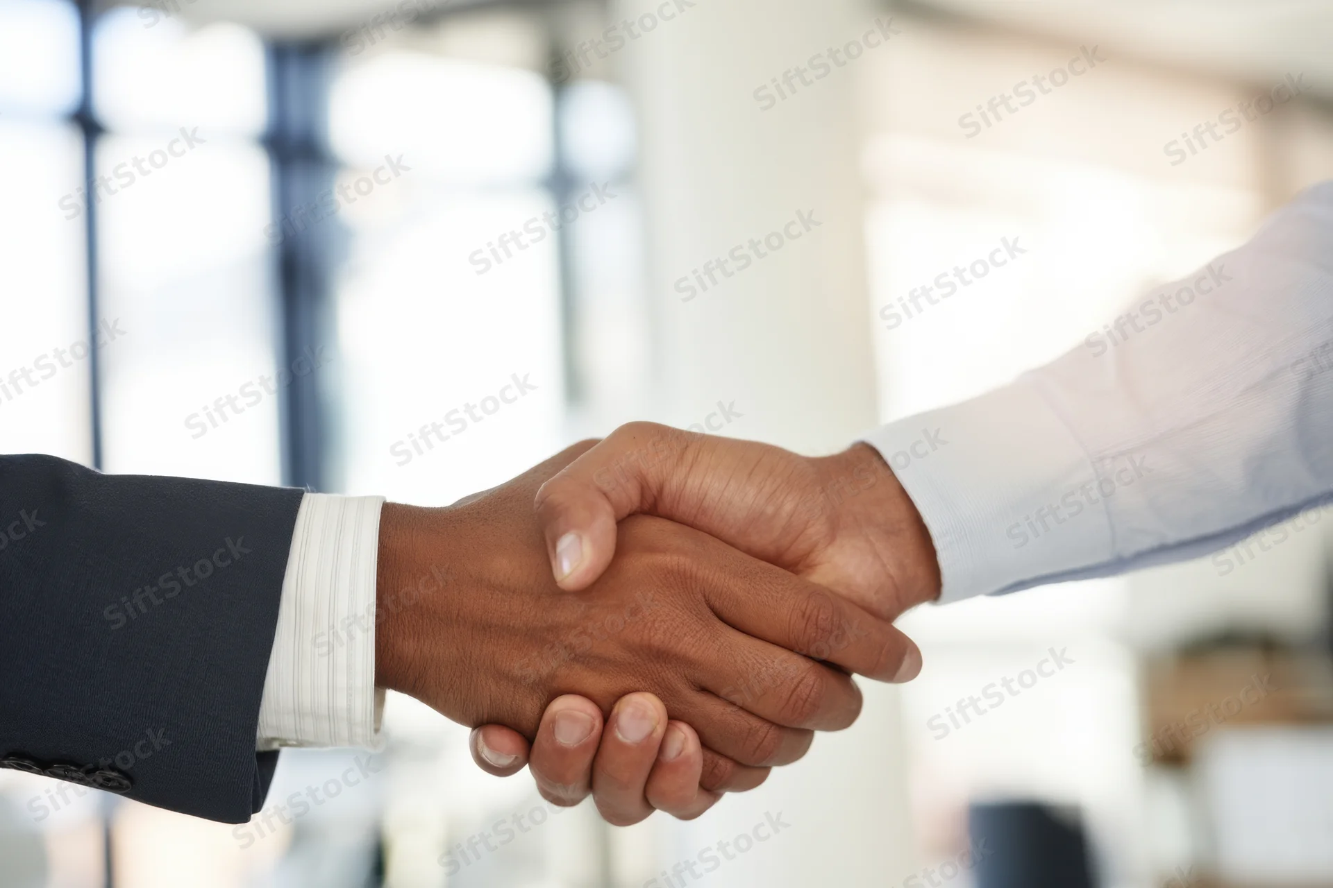 Two professionals shaking hands in a bright modern office