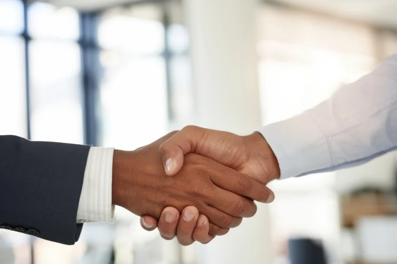 Two professionals shaking hands in a bright modern office